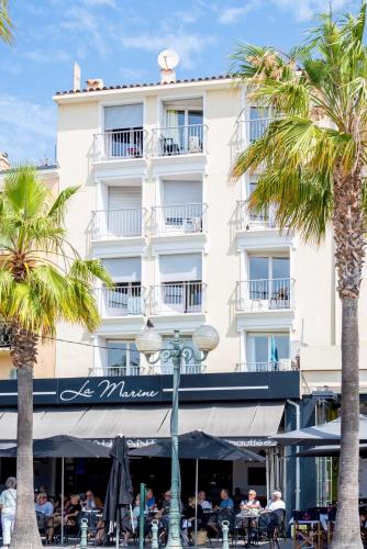 un grand bâtiment blanc avec des palmiers devant dans l'établissement Studio au port de Sanary, à Sanary-sur-Mer