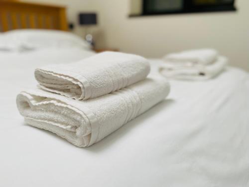 three white towels sitting on top of a bed at Hodder Cottage in The Ribble Valley in Whalley