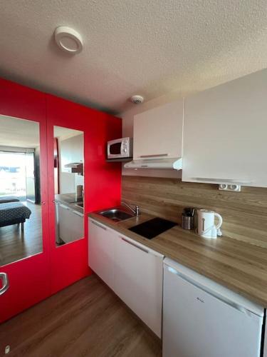 - une cuisine avec des placards blancs et des murs rouges dans l'établissement JOIA Bassin d'Arcachon- NOTRO 209, à La Teste-de-Buch