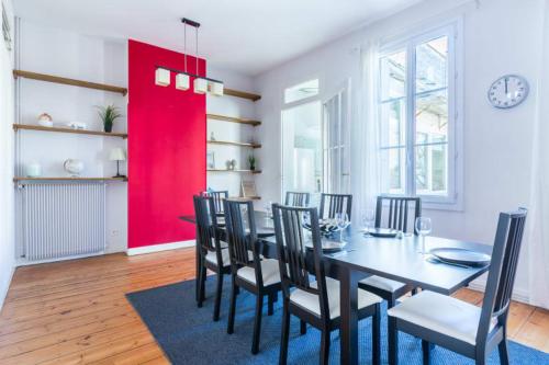d'une salle à manger avec une table, des chaises et un mur rouge. dans l'établissement GuestReady - Duplex lumineux et spacieux, 7 personnes, à Bordeaux
