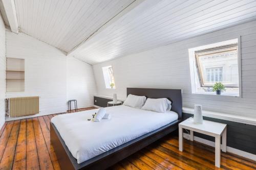une chambre avec un grand lit dans une pièce blanche dans l'établissement GuestReady - Duplex lumineux et spacieux, 7 personnes, à Bordeaux