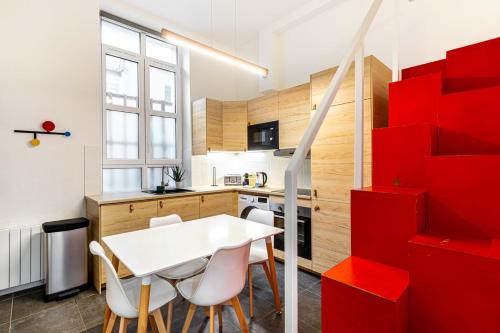 une cuisine avec une table blanche et des étagères rouges dans l'établissement Disponible - Paris - All Equipped Souplex - From 1 to 6 Guests - Entry from 3pm - Departure up to 11am, à Paris
