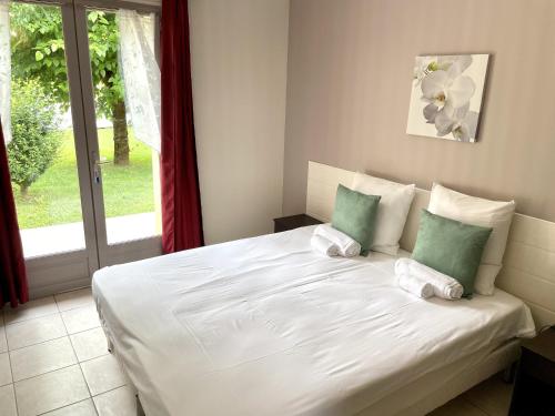 a white bed in a room with a window at Gîte La Sarrazine - Dordogne in Carlux