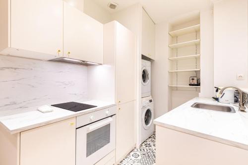 - une cuisine blanche avec un évier, un lave-linge et un sèche-linge dans l'établissement GuestReady - Lovely Parisian Apartment for 4pax., à Paris