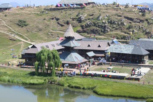 ein großes Gebäude auf einem Hügel neben einem Fluss in der Unterkunft Parashar lake Fogg hill Resort in Prashar lake