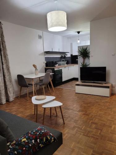 un salon avec un canapé et une table et une cuisine dans l'établissement Appartement en résidence - centre ville de Limoges, à Limoges