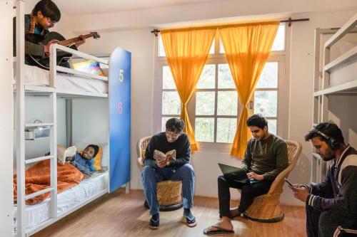 a group of people sitting in a room with a bunk bed at Oak Land House in Manāli