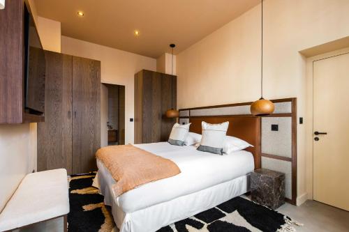 Cette chambre comprend un grand lit avec des draps blancs et une couverture orange. dans l'établissement Magnificent apt - 3BD-8P - Coeur du Marais, à Paris