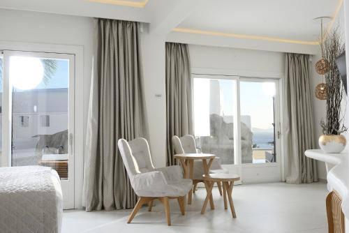 a bedroom with white furniture and a table and chairs at Anax Resort and Spa in Agios Ioannis Mykonos