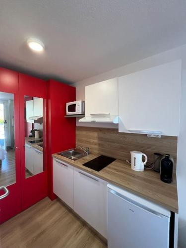 - une cuisine avec des placards blancs et des murs rouges dans l'établissement JOIA Bassin d'Arcachon - NOTRO 221, à La Teste-de-Buch