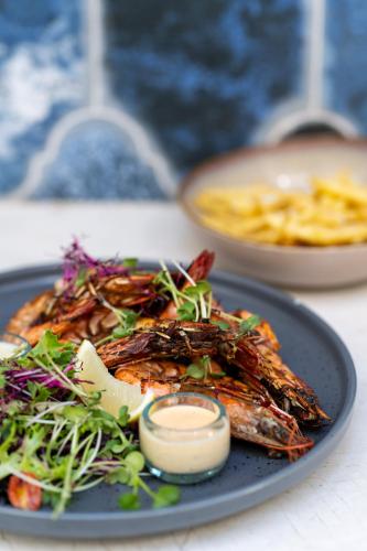 a plate of food with seafood and vegetables on a table at The Neela Boutique Hotel Stone Town in Zanzibar City