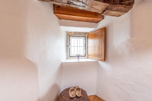 a room with a window and a pair of shoes at GuestReady - Lampas Wind Mill in Colares