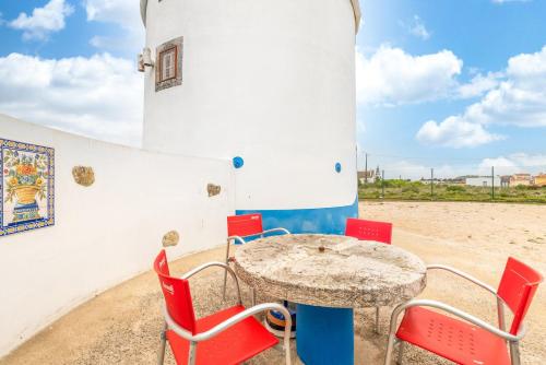 a table and chairs in front of a lighthouse at GuestReady - Lampas Wind Mill in Colares