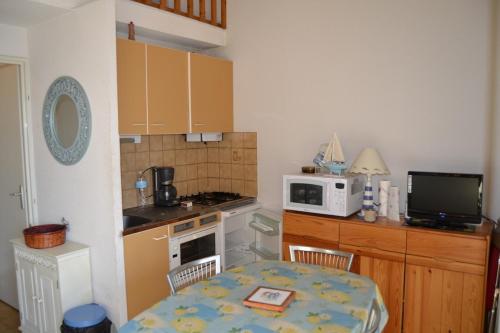 une petite cuisine avec une table et un micro-ondes dans l'établissement 030 Jean Bart 54, au Cap d'Agde