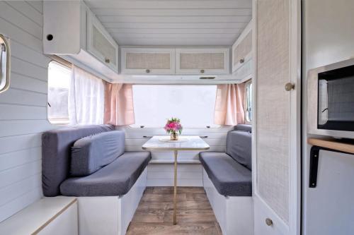 une petite salle à manger dans une petite caravane avec des chaises bleues et une table dans l'établissement L'échappée Belle, à Saint-Maudez