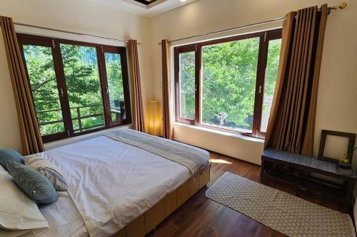 a bedroom with a bed and two large windows at Paldan Orchids in Leh