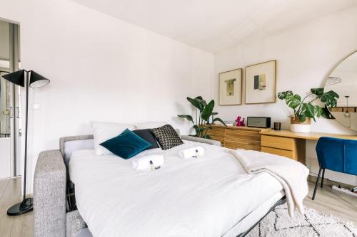 une chambre blanche avec un lit et un bureau dans l'établissement GuestReady - Appartement de charme au dernier étage, à Paris