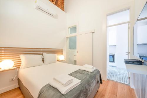 una camera da letto con un letto bianco e una grande finestra di GuestReady - Urban Garden Apartments a Lisbona