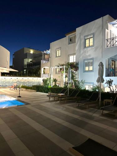 a white building with tables and chairs and a pool at Evdokia Suites in Gouves