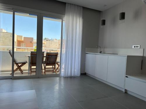 a kitchen with white cabinets and a table with chairs at Evdokia Suites in Gouves