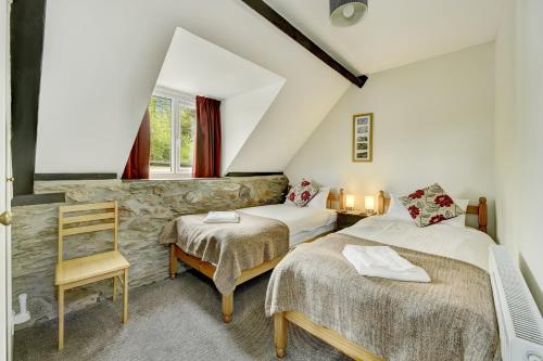 a attic bedroom with two beds and a chair at Dunkery Cottage Wheddon Cross in Minehead