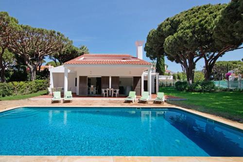 a swimming pool in front of a house at Villa Lynn - Quadradinhos in Almancil