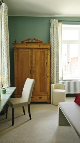 a living room with a cabinet and a white chair at Winzerhof Ross & Rose in Trechtingshausen