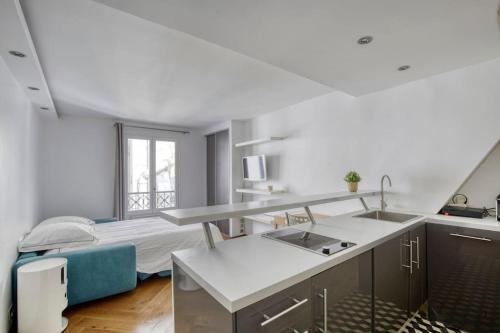 - une cuisine avec évier et un lit dans une chambre dans l'établissement Studio Charmant à Deux Pas de l'Élysée Luxe et Confort au Cœur de Paris, à Paris
