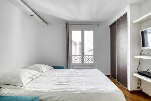 une chambre avec un grand lit blanc et une fenêtre dans l'établissement Studio Charmant à Deux Pas de l'Élysée Luxe et Confort au Cœur de Paris, à Paris