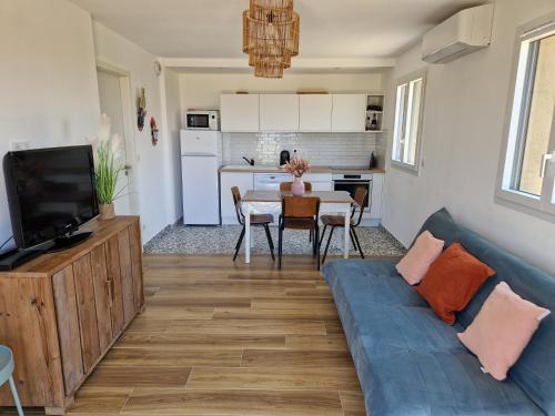 un salon avec un canapé bleu et une cuisine dans l'établissement T2 Neuf climatisé dans villa à Corbara, à Corbara