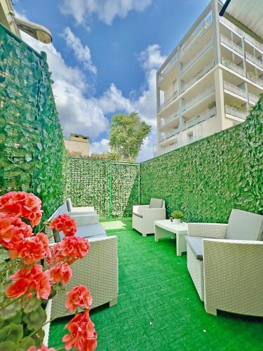 a patio with white chairs and red flowers in front of a wall at Vigentino Suites in Milan