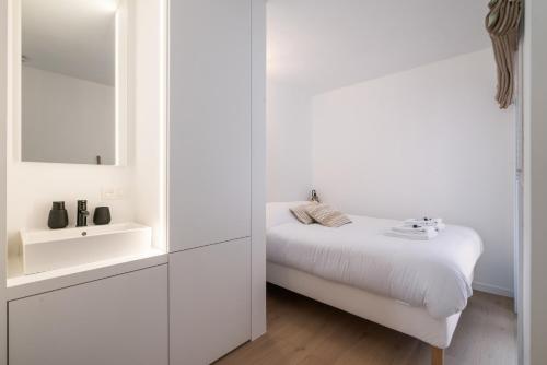 a white bathroom with a bed and a sink at Luxe zeeverblijf op 1min van het strand - 5p in Knokke-Heist