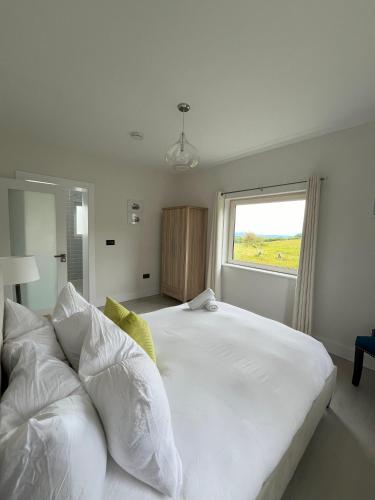a bedroom with a large white bed with a window at Kathleen's Carrowkeel Cottage in Sligo