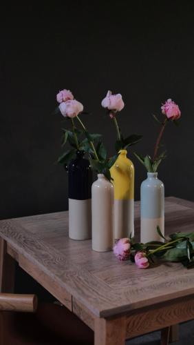 a wooden table with four vases with flowers in them at Moulin Renaudiots - Maison d'hôtes in Autun