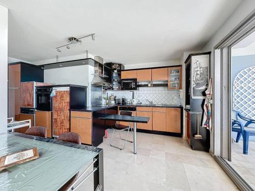 une grande cuisine avec des placards en bois et une table dans l'établissement Appartement T3 avec climatisation et parking à La Ciotat (4 pers) - FR-1-770-17, à La Ciotat