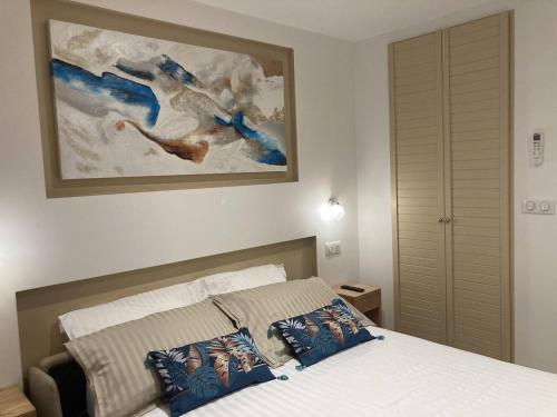 une chambre avec un lit et un tableau au mur dans l'établissement Studio climatisé à 200m de la plage avec balcon, parking et ménage inclus - Bormes-les-Mimosas - FR-1-251-836, à Bormes-les-Mimosas