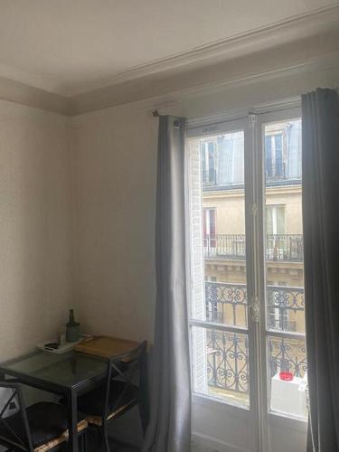 Cette chambre dispose d'une fenêtre avec une table et une table. dans l'établissement Élégance et Confort proche Bastille, à Paris