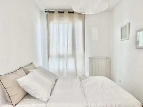 un lit avec des draps blancs et des oreillers dans une chambre dans l'établissement M43 Marquer Joli T3 proche du centre ville d'Annemasse, à Annemasse