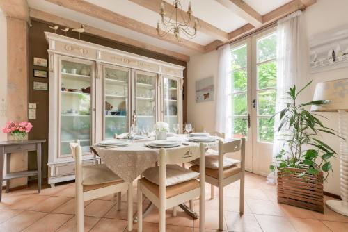 une salle à manger avec une table, des chaises et des fenêtres dans l'établissement À 400m de la plage, maison pour 8 avec piscine, à Andernos-les-Bains