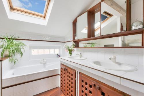 une salle de bain avec deux lavabos et un grand miroir dans l'établissement À 400m de la plage, maison pour 8 avec piscine, à Andernos-les-Bains