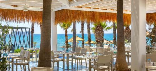 a restaurant with tables and chairs and palm trees at The GrandResort - Limited Edition by Leonardo Hotels in Limassol