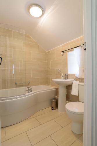 a bathroom with a tub and a toilet and a sink at Brackendale Cottage Upperdale Peak District in Cressbrook