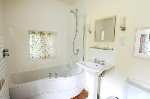 a white bathroom with a tub and a sink at Park CottageChatsworth Estate in Baslow