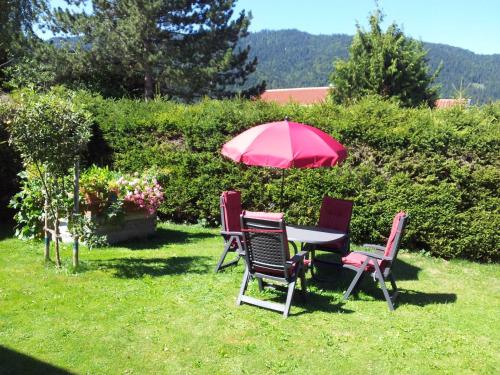 a table and chairs with a red umbrella in the grass at Ferienwohnung Haulle, Kreuth-Scharling am Tegernsee in Kreuth