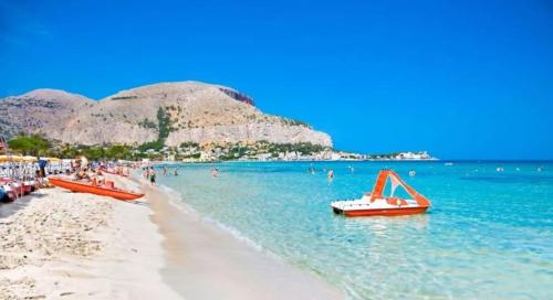 people on a beach with boats in the water at Menzel el Emir in Misilmeri