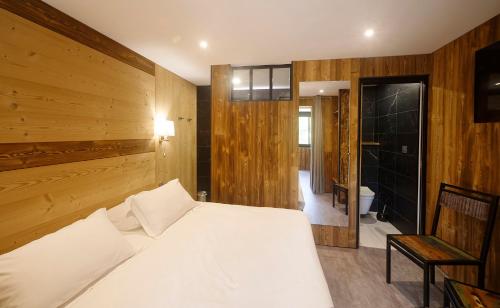 a bedroom with a white bed and wooden walls at Hotel du Lac Foix in Foix