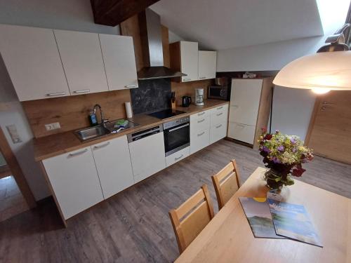 a kitchen with white cabinets and a table with flowers on it at Unterhofgut in Goldegg