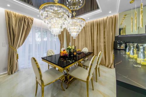 a dining room with a black table and chairs and chandeliers at Willa z jacuzzi na polu golfowym Sierra Golf Homessimo Stars in Gowino