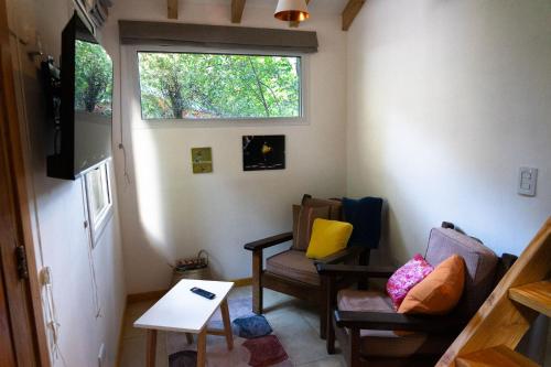 Una sala de estar con dos sillas y una ventana. en Casa en el Bosque, en San Carlos de Bariloche