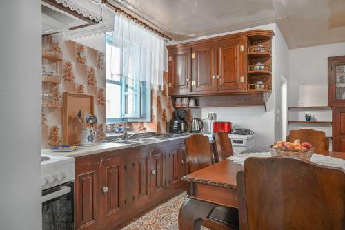 a kitchen with wooden cabinets and a sink and a table at Anoi Traditional House Patmos Architectural Charm in Patmos
